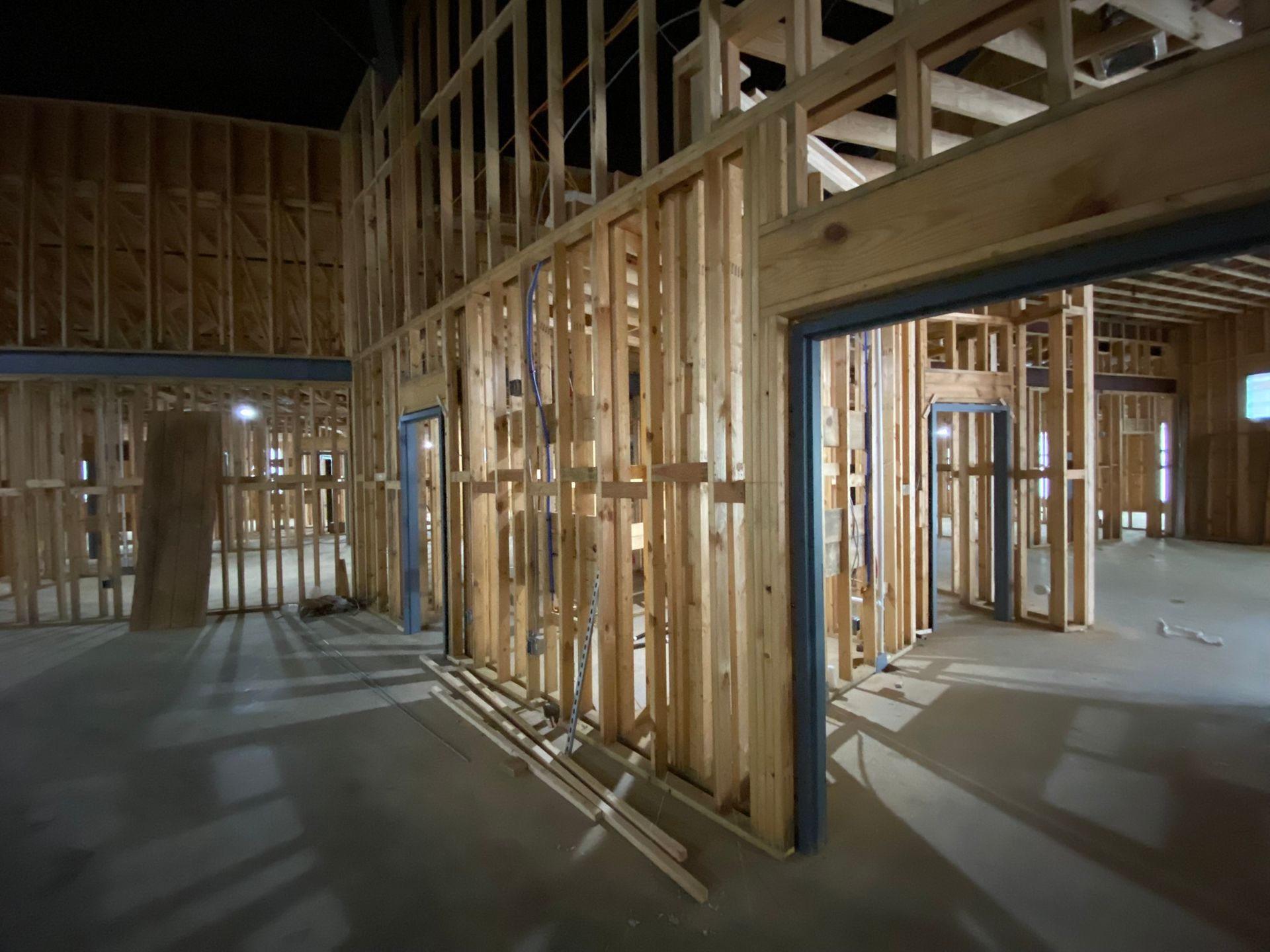 The inside of a building under construction at night with wooden walls and doors.