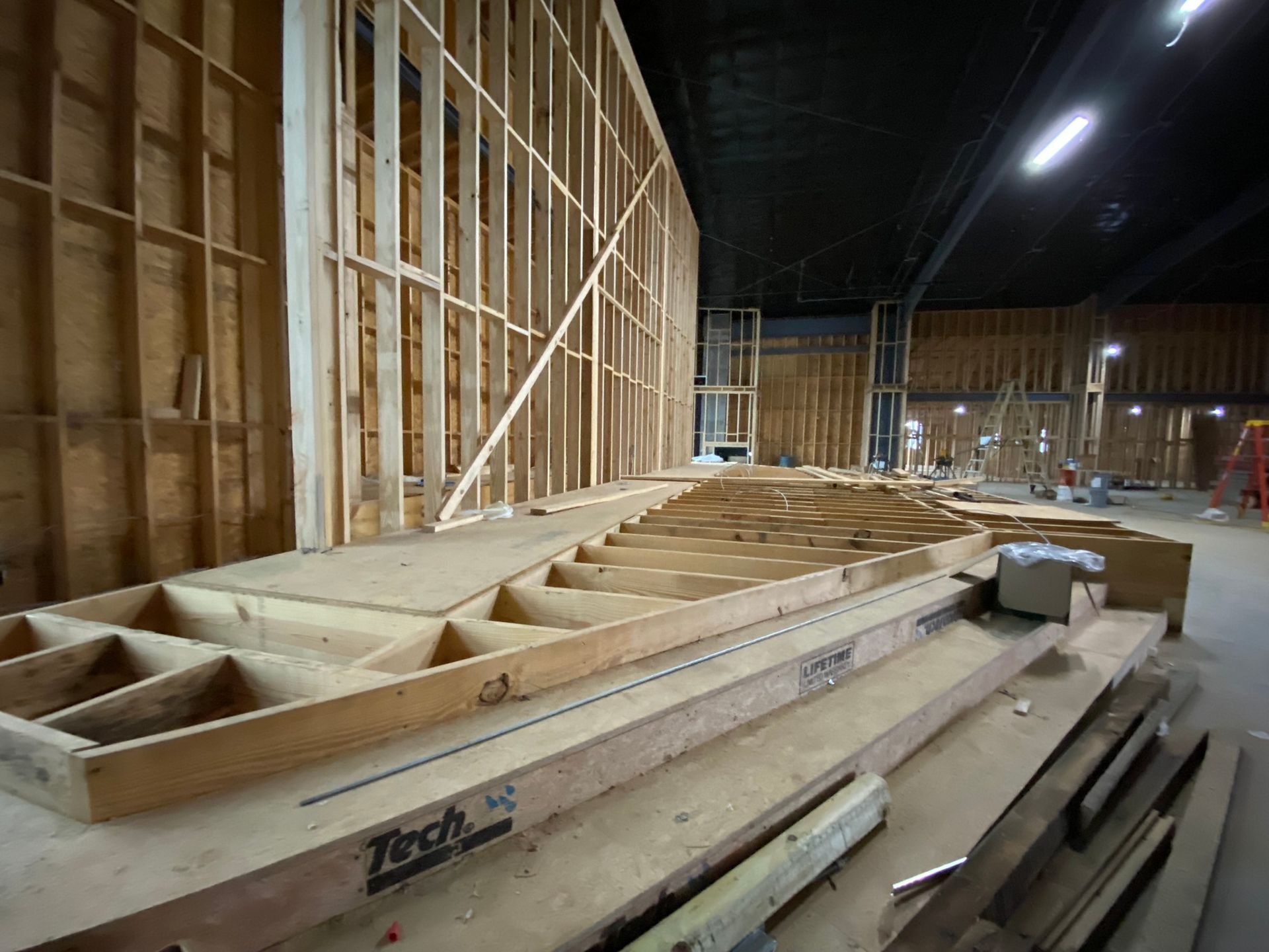 A large wooden structure is being built in a warehouse.
