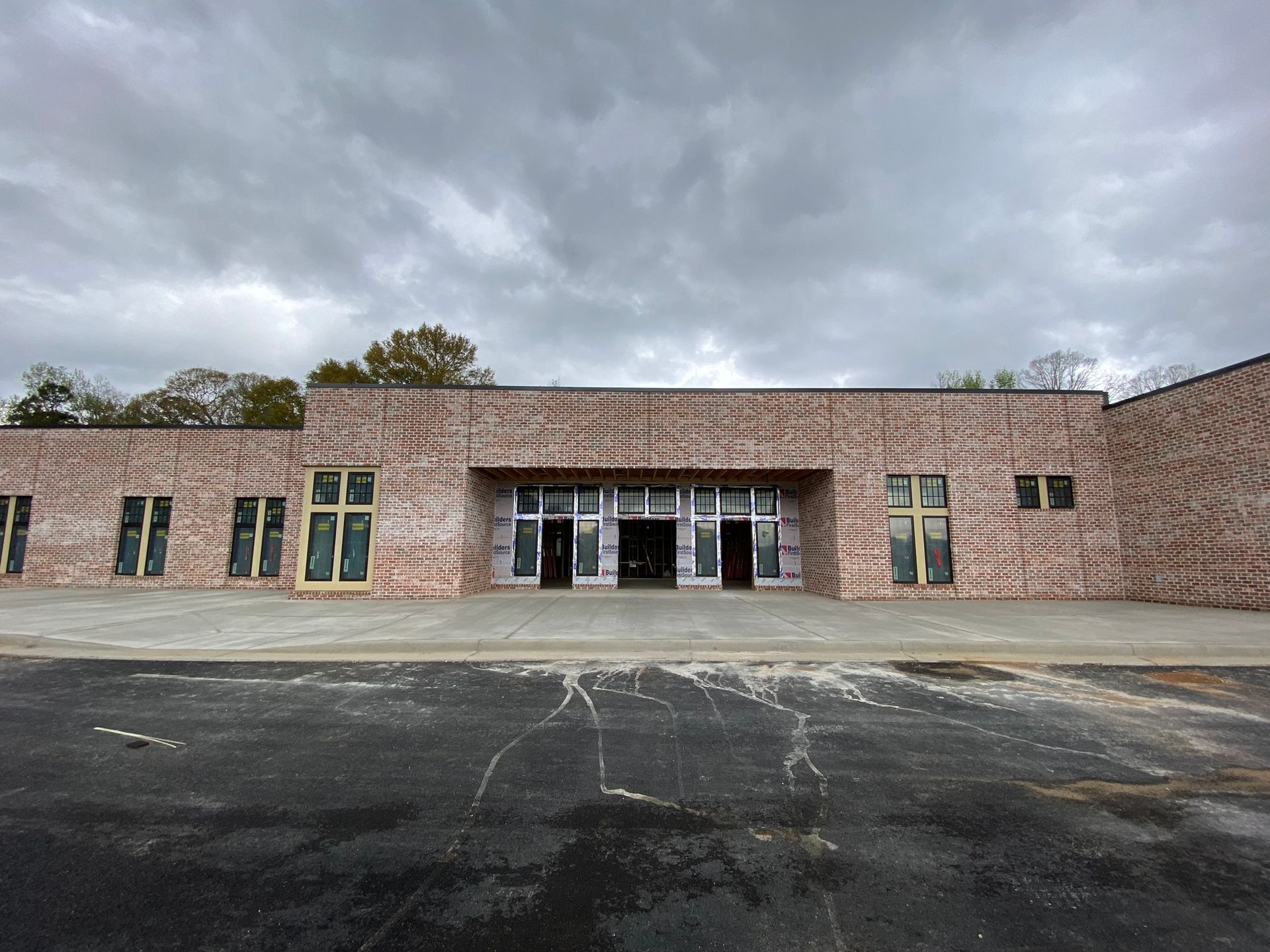 A large brick building with a lot of windows and a cloudy sky in the background.