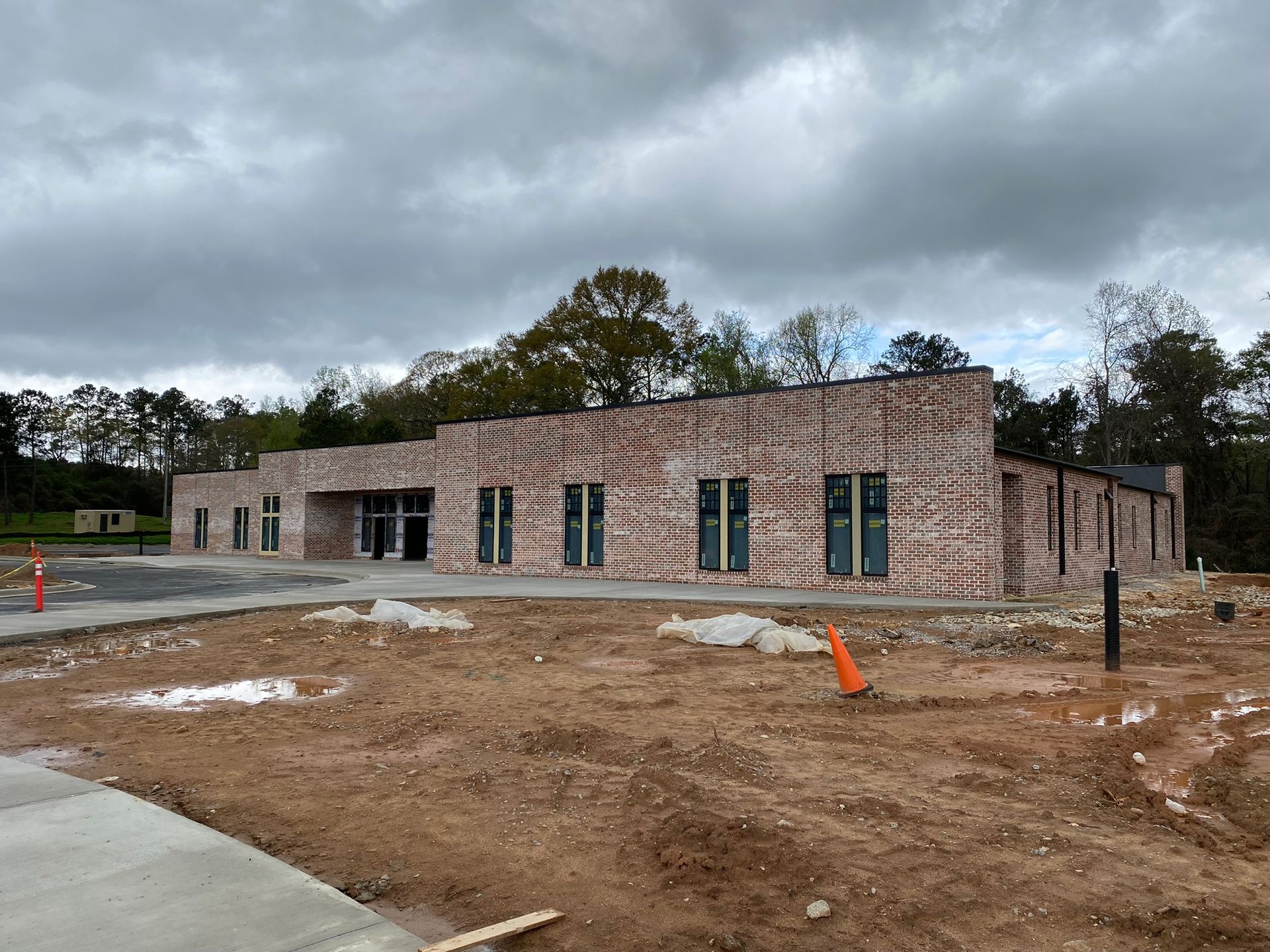 A large brick building is being built in a dirt field.