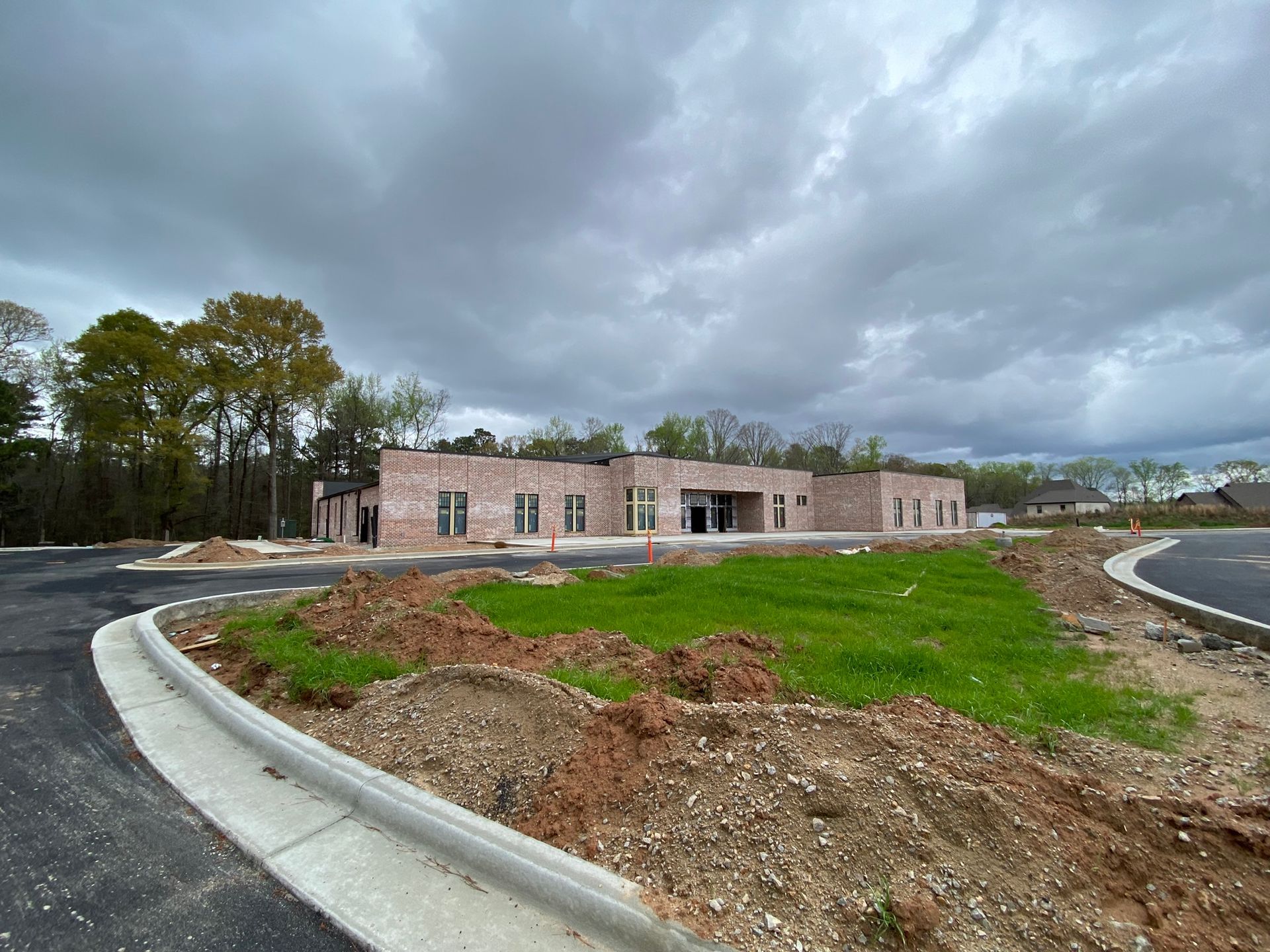 A large brick building is being built in the middle of a grassy field.