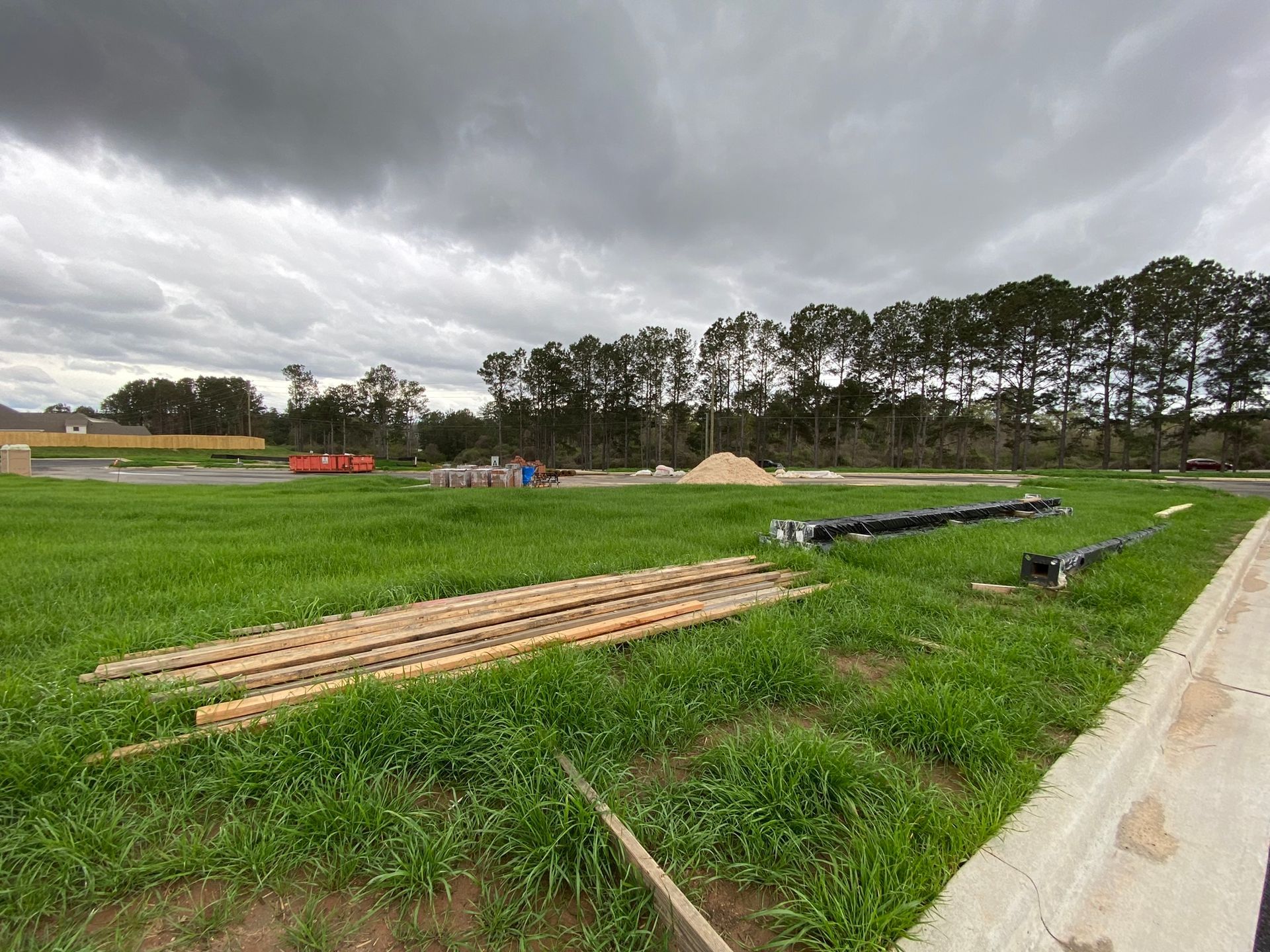 A large grassy field with a wooden fence in the foreground and a cloudy sky in the background.