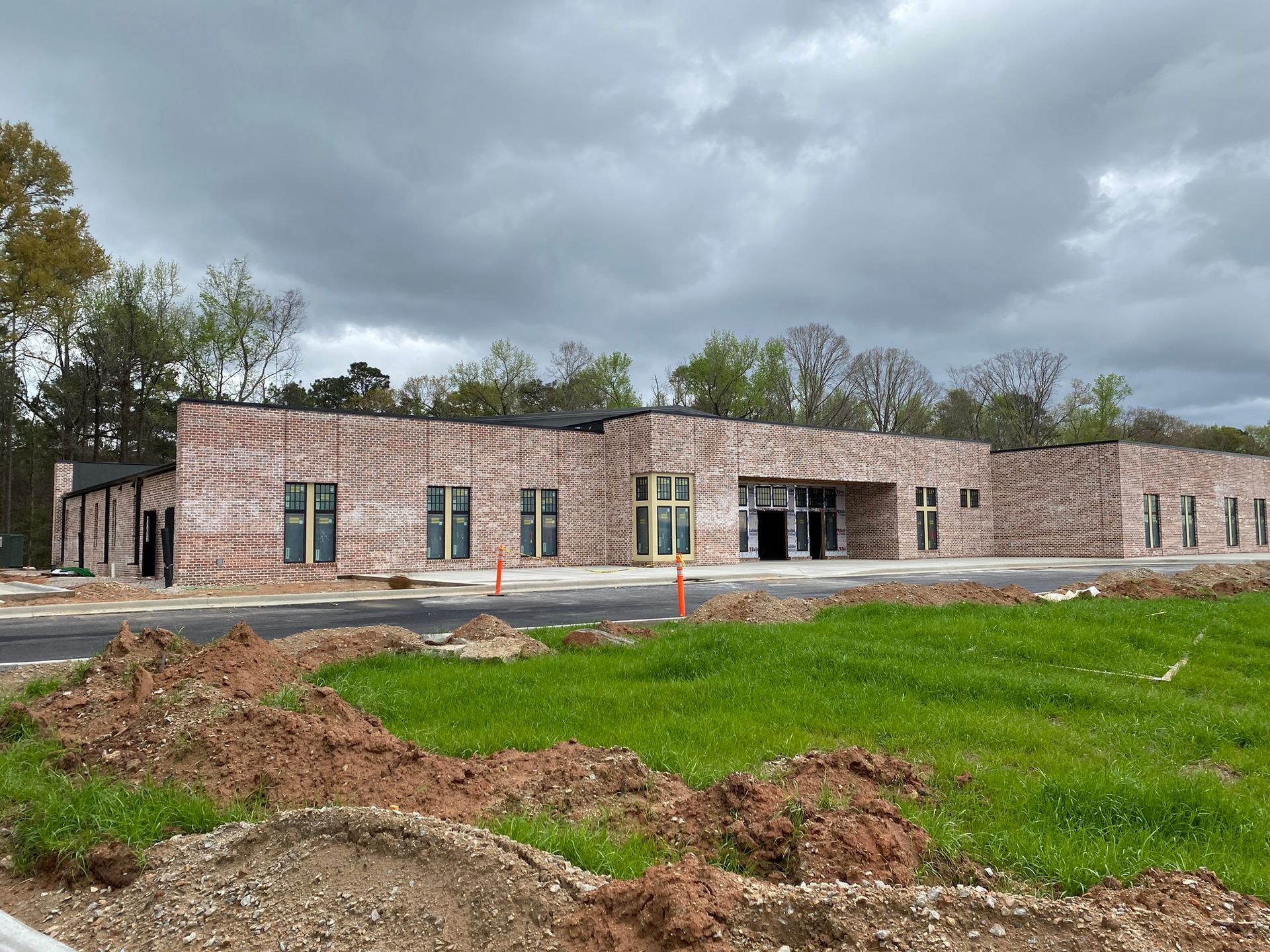 A large brick building is being built in the middle of a grassy field.