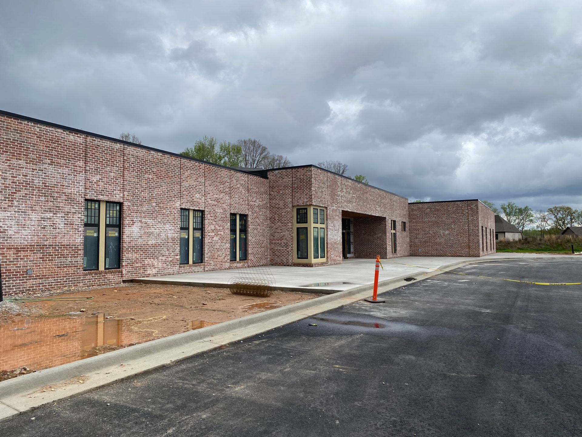 A brick building with a lot of windows is under construction on a cloudy day.