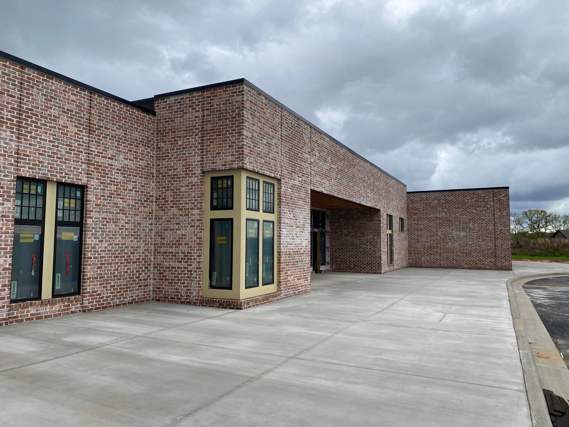 A large brick building with a concrete driveway in front of it.