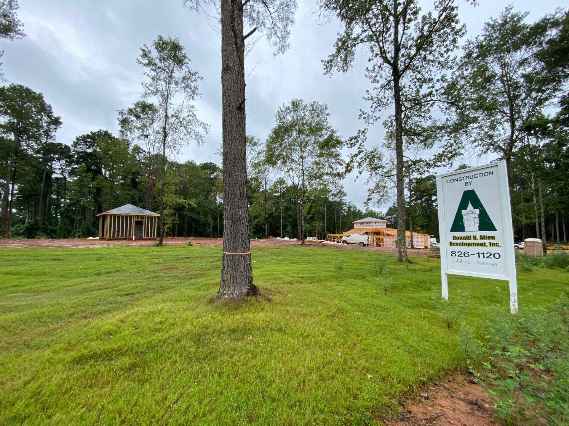 A sign in the middle of a grassy field with trees in the background.