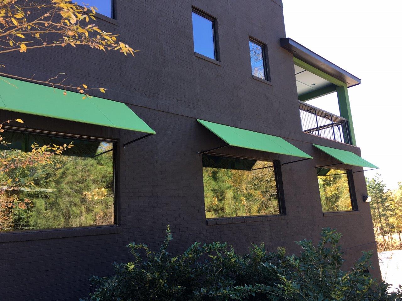 A black building with green awnings on the windows