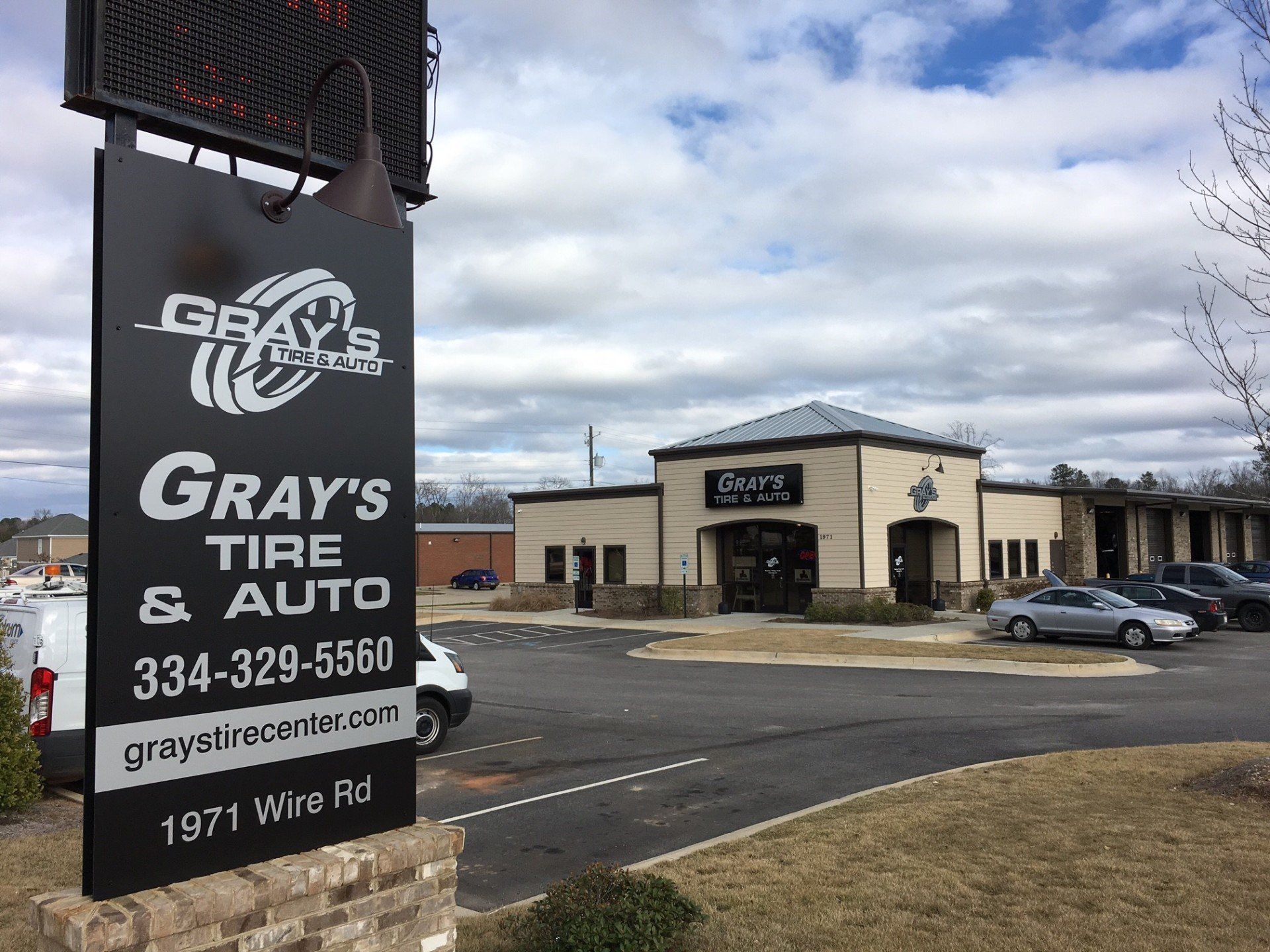 A sign for gray 's tire and auto is in front of a building.