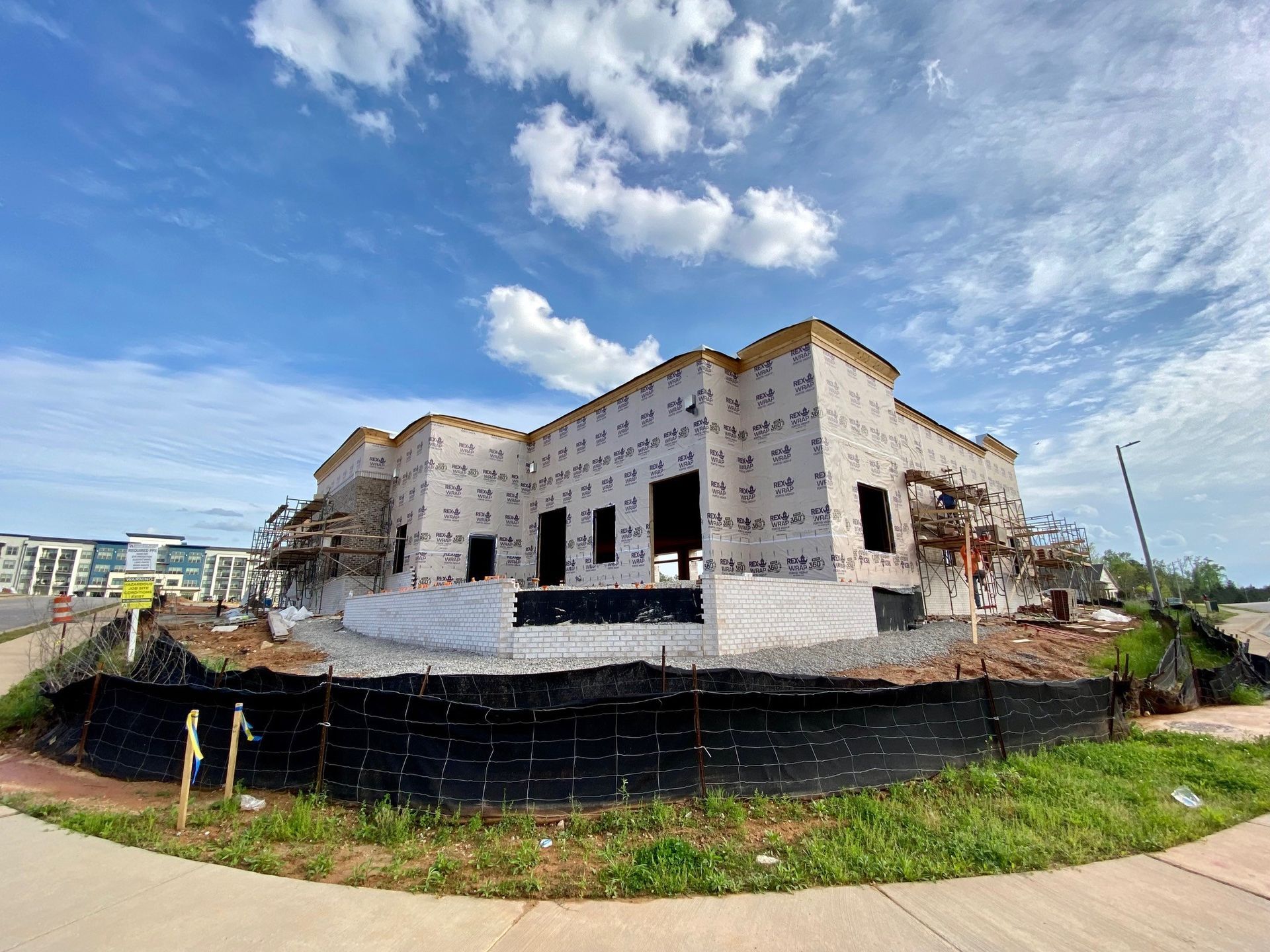 A large building is being built next to a sidewalk.