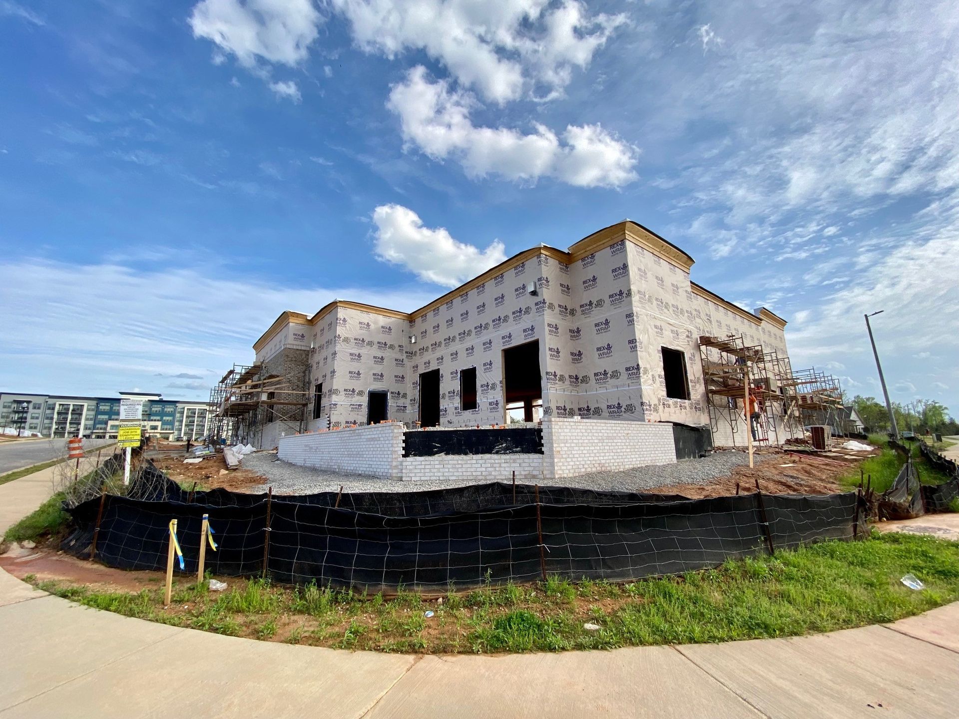 A large building is being built next to a sidewalk.