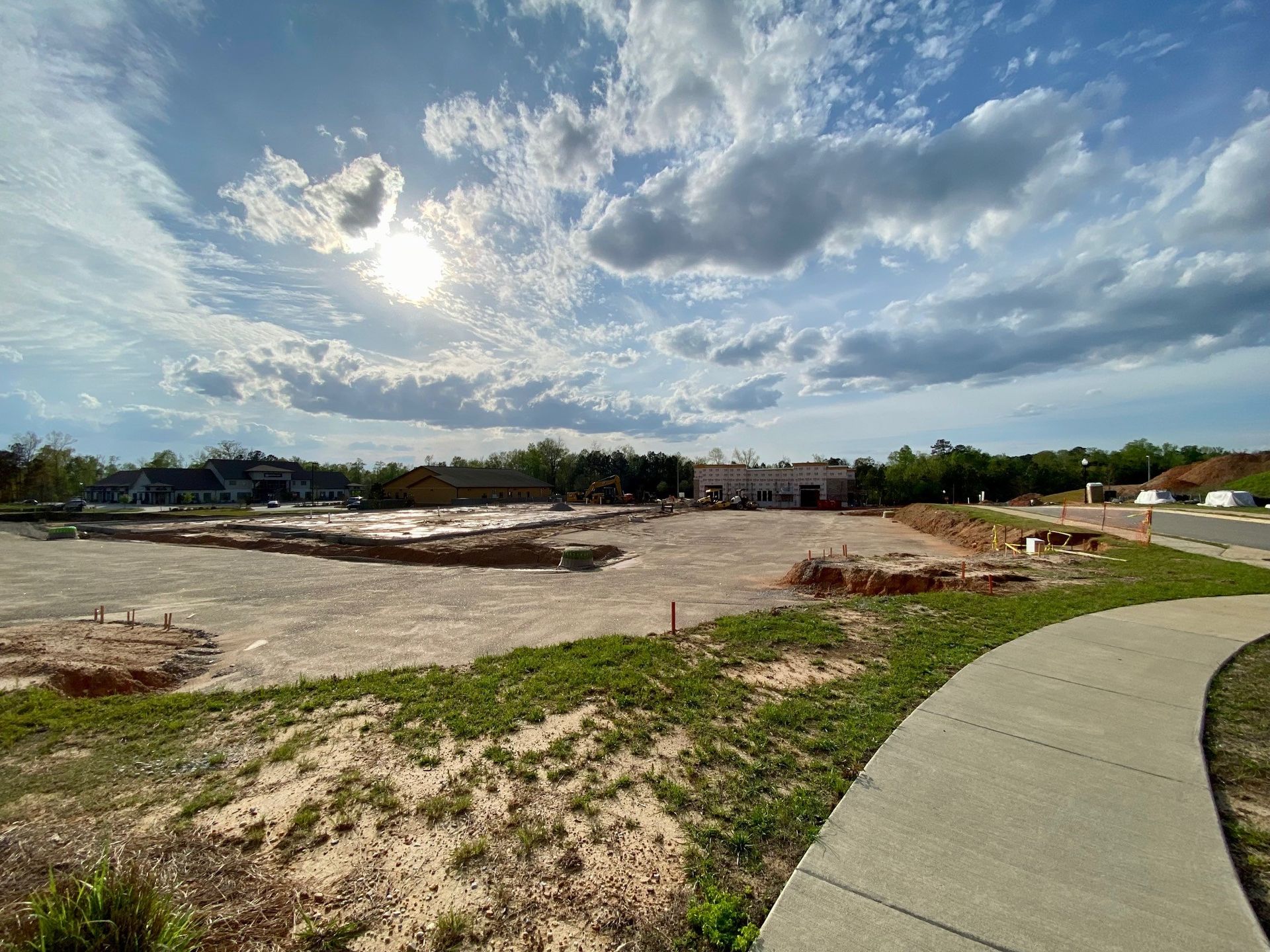 The sun is shining through the clouds over a construction site.