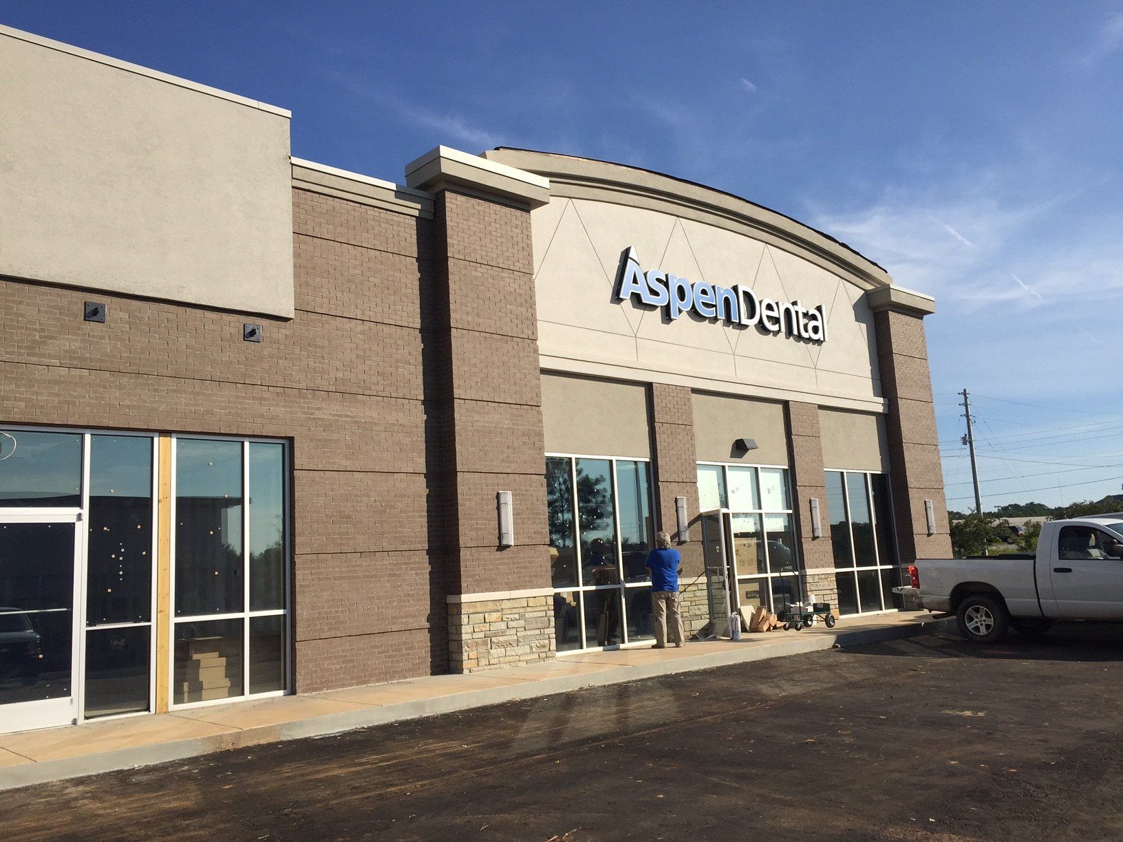 A man is standing in front of a building that says aspendental