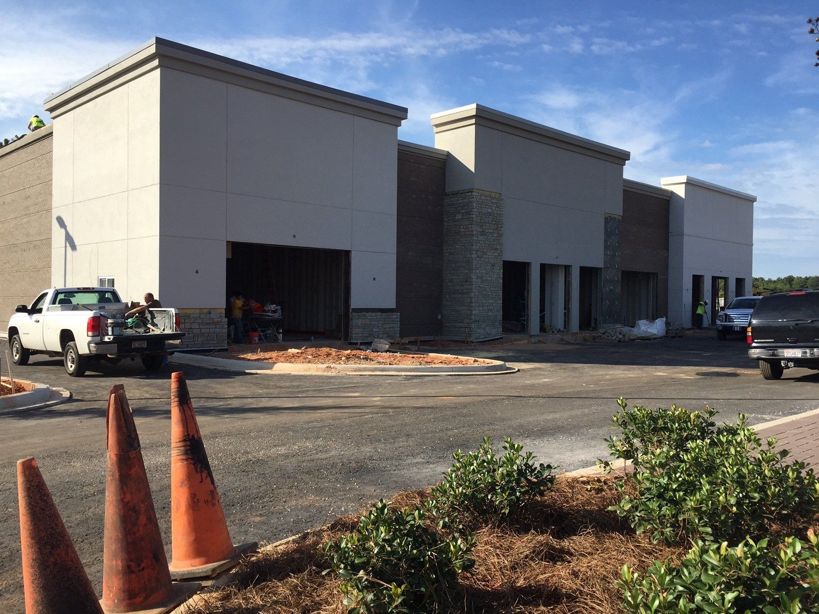 A white truck is parked in front of a building under construction.