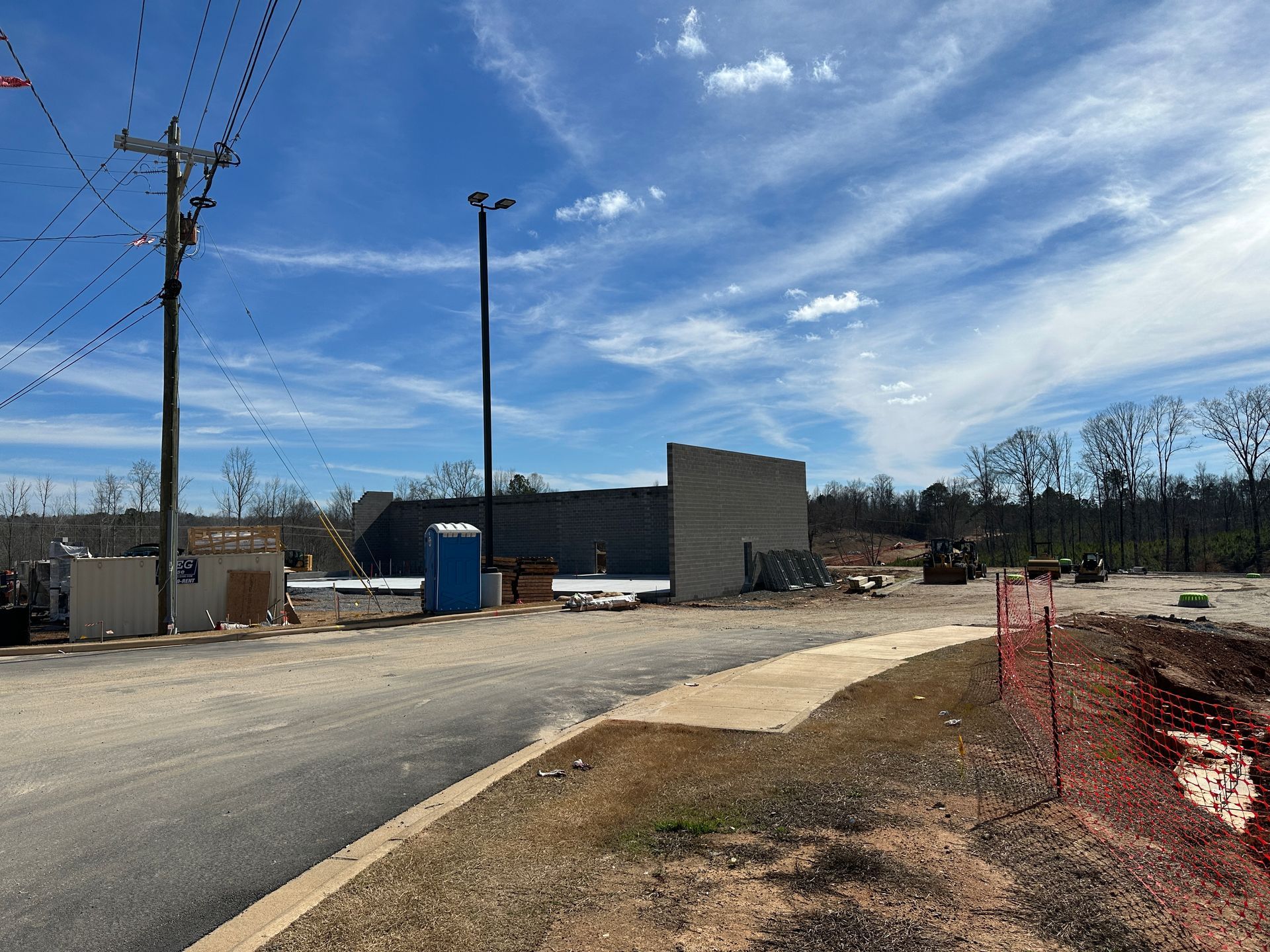 Construction site with unfinished building, utility poles, and blue sky.