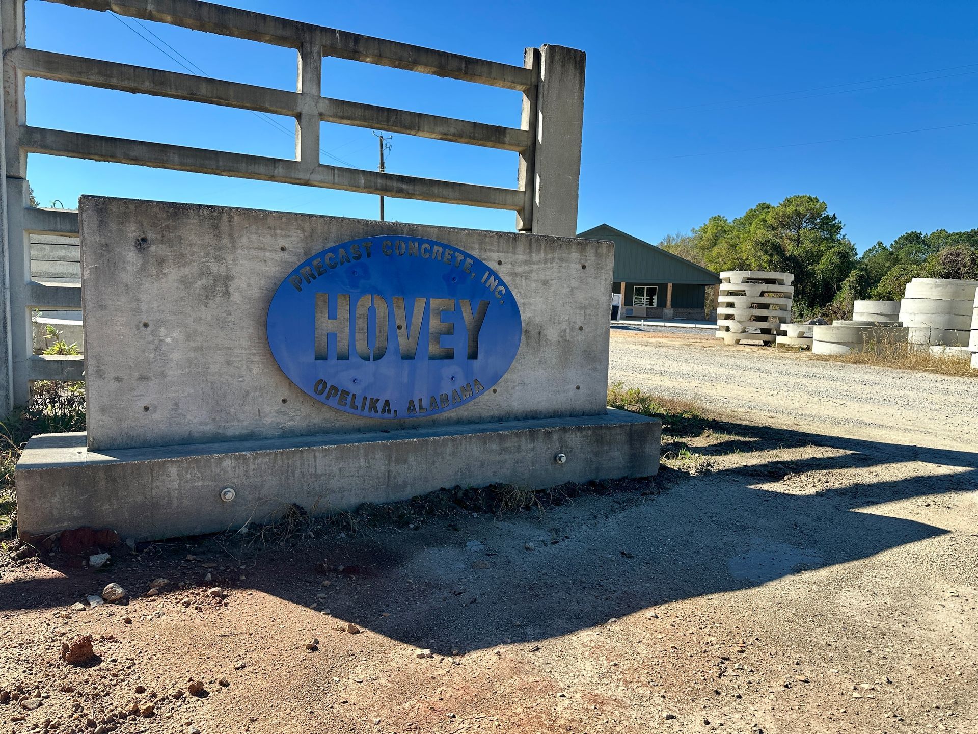 An aerial view of a new Hovey Precast office building with a blue roof surrounded by trees.