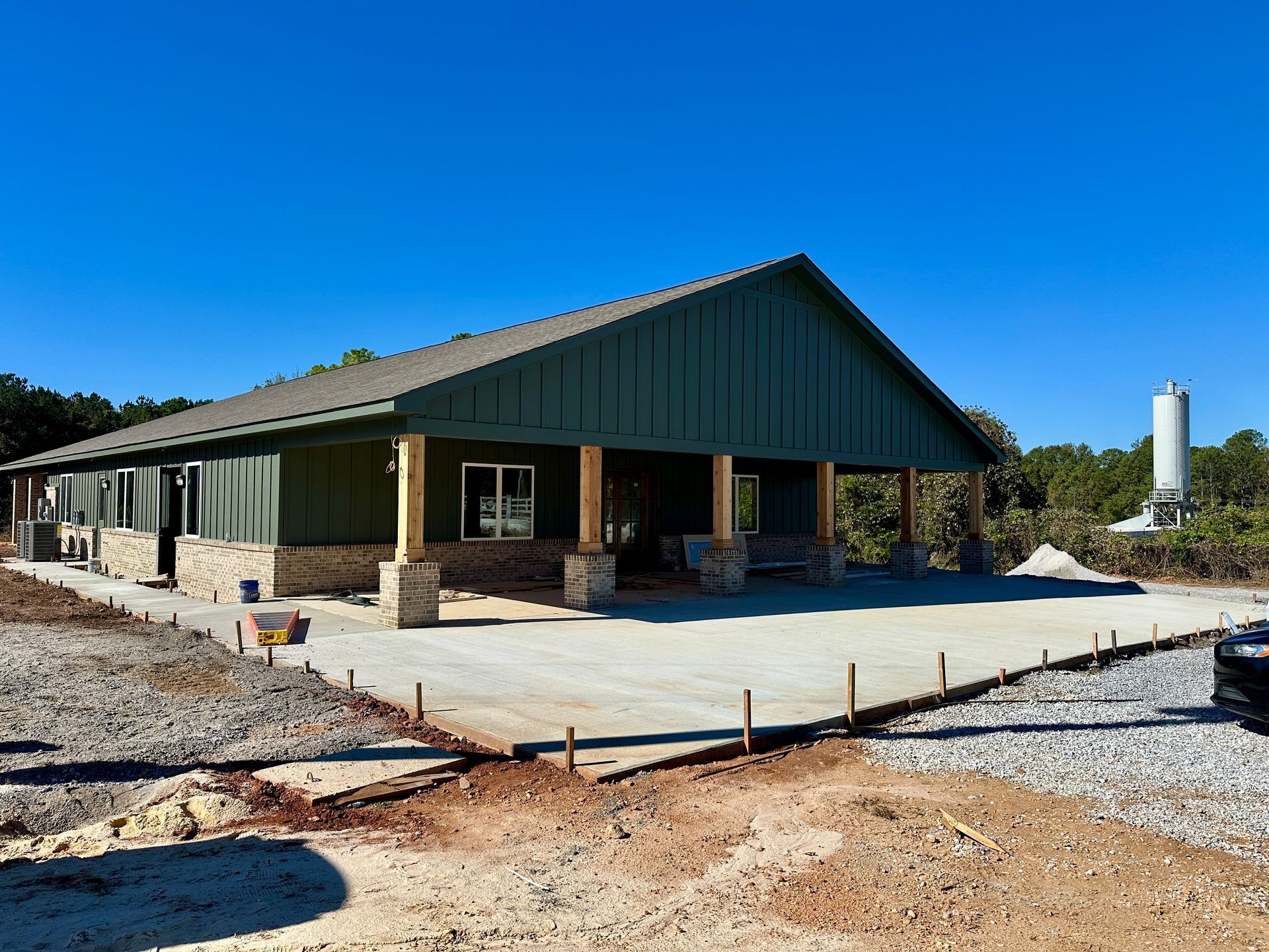 New building under construction with a green roof and brown pillars.