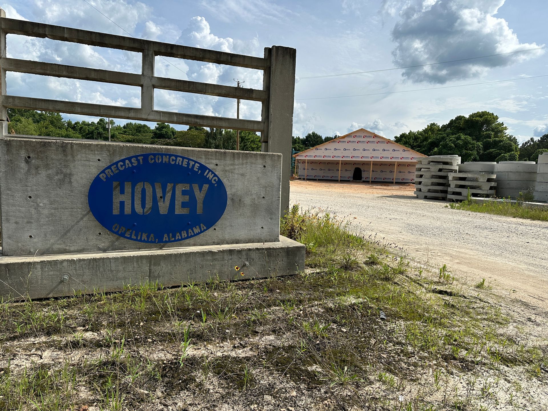 An aerial view of a new Hovey Precast office building with a blue roof surrounded by trees.