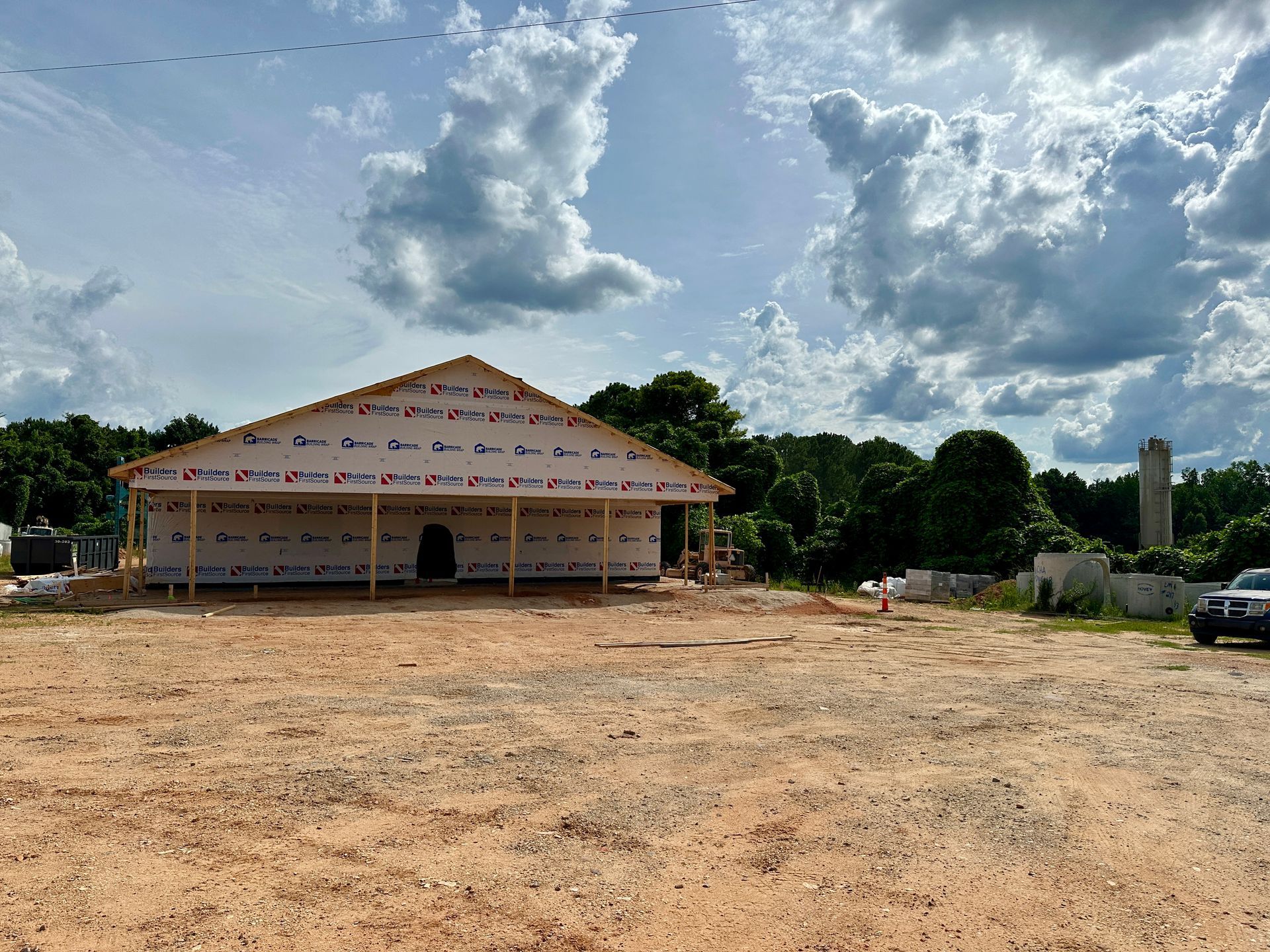 A large building is being built in the middle of a dirt field.