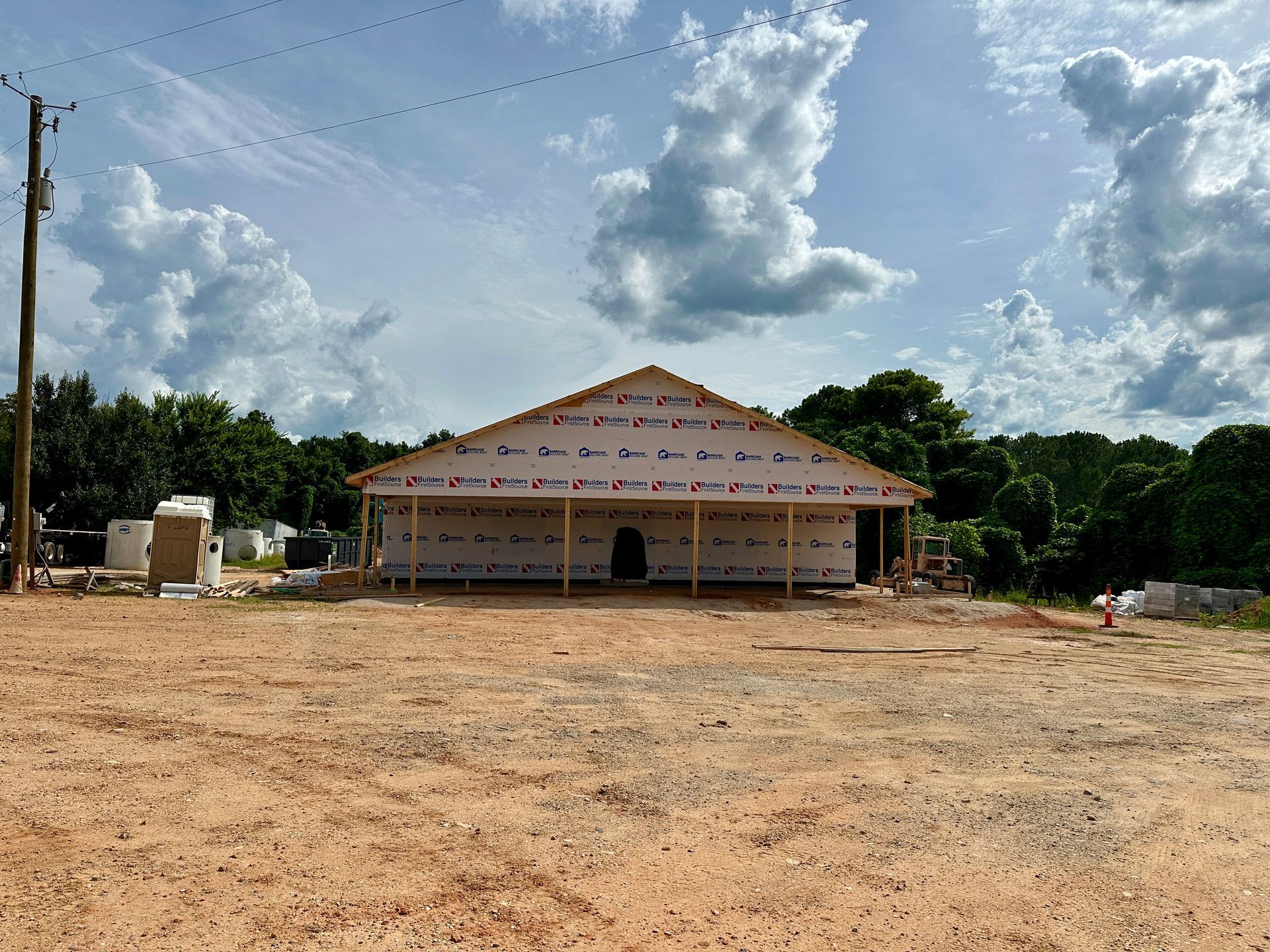 A large building is being built in the middle of a dirt field