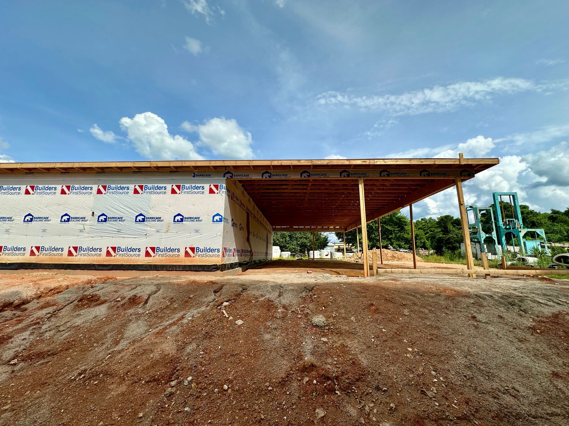 A building is being built in a dirt field with a blue sky in the background.