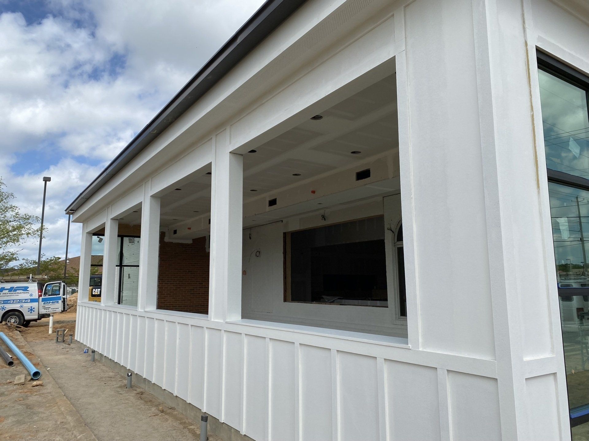 A white building with a lot of windows and a white van parked in front of it.