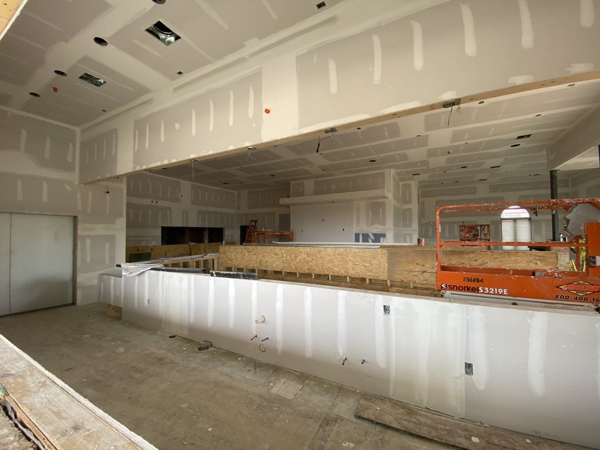 A large empty room with drywall walls and a ladder