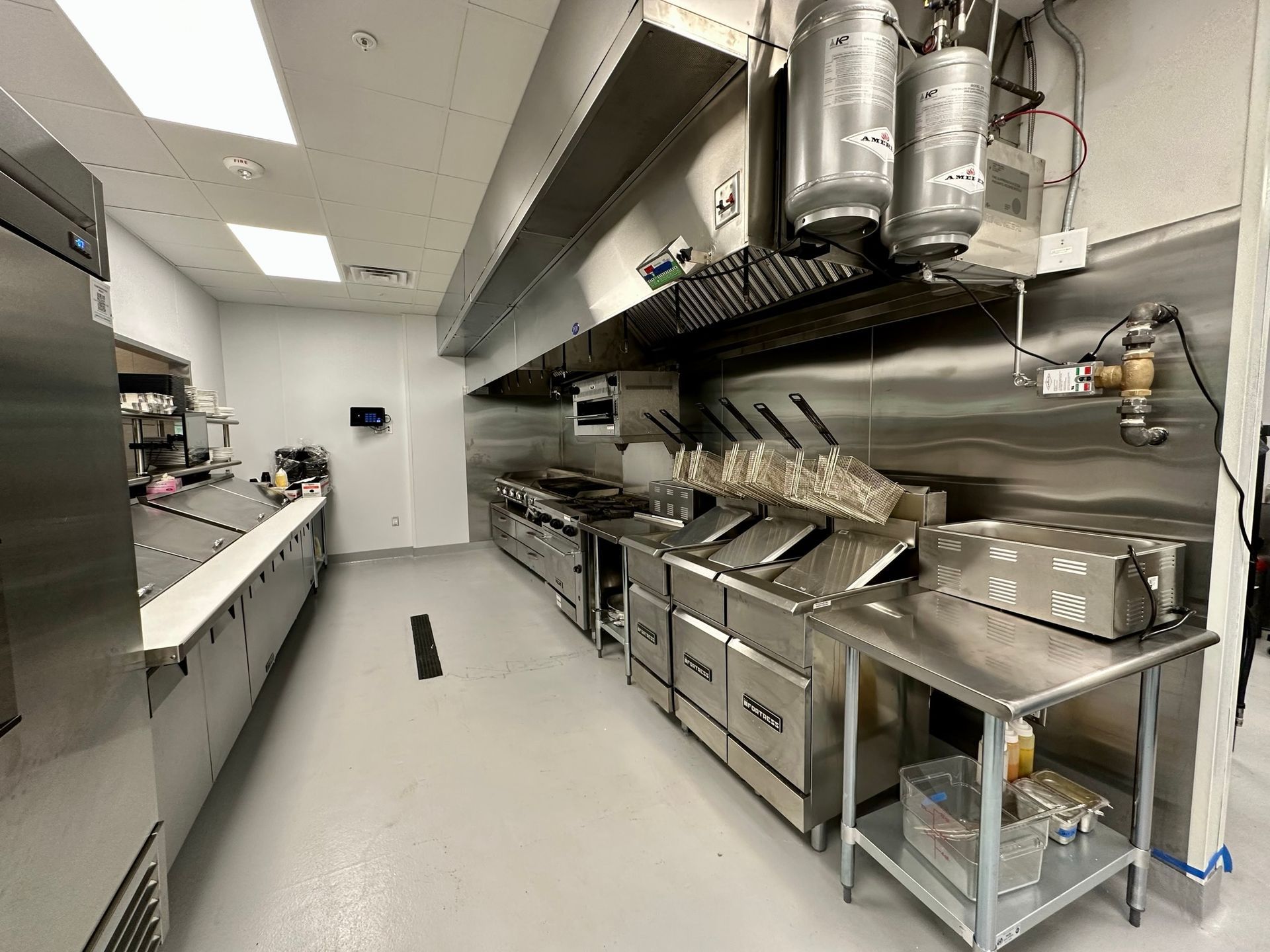 A long kitchen with stainless steel appliances and a refrigerator.