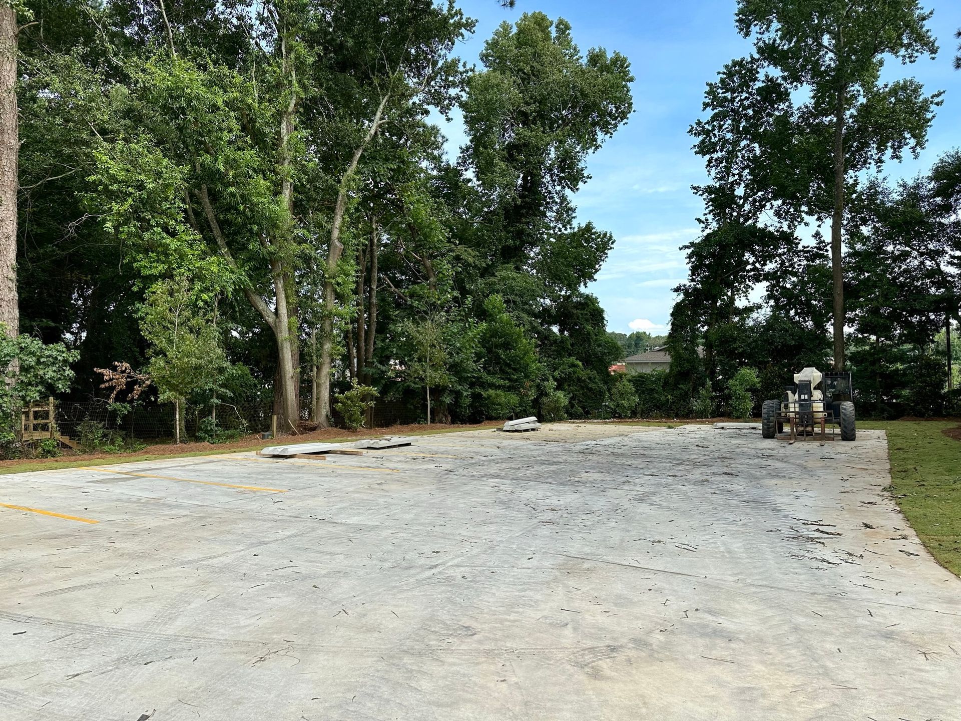 An empty parking lot with trees in the background