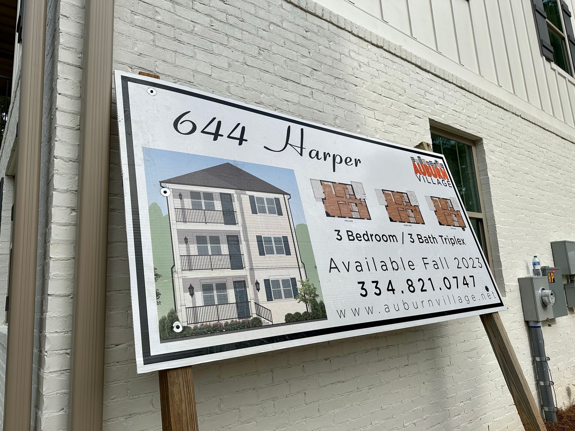 A sign on a brick building advertising a house for sale