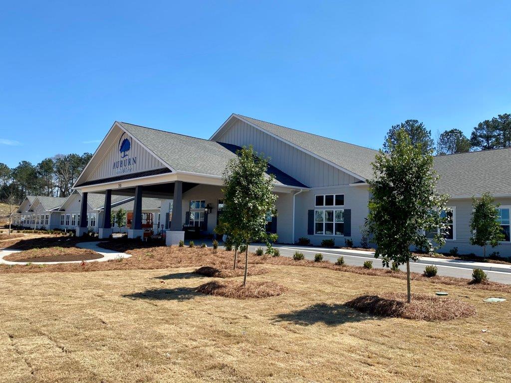 A large white building with a porch and trees in front of it.