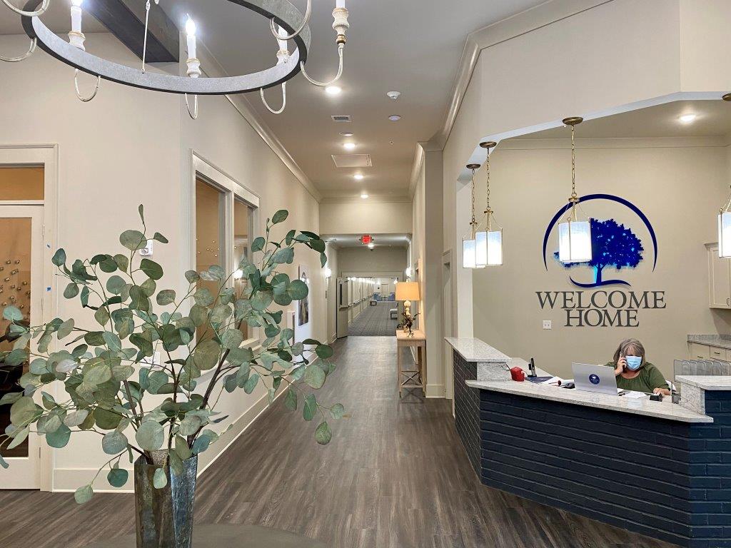A long hallway with a reception desk and a sign that says welcome home.