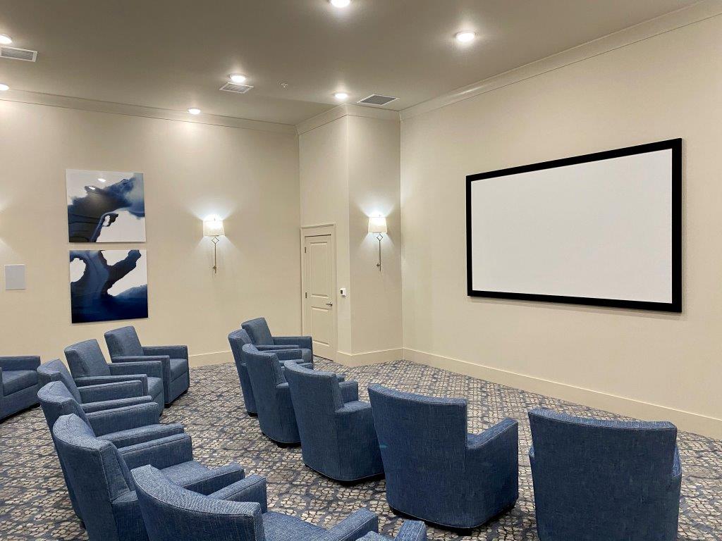 A movie theater with blue chairs and a large screen.