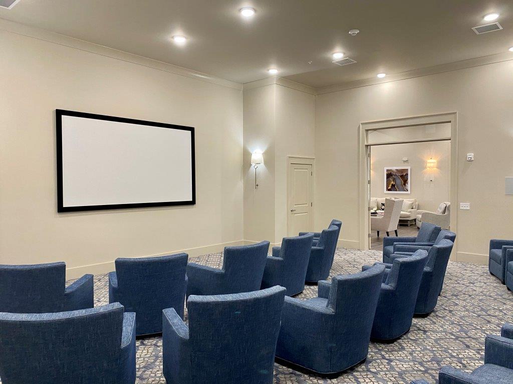 A movie theater with blue chairs and a large screen.