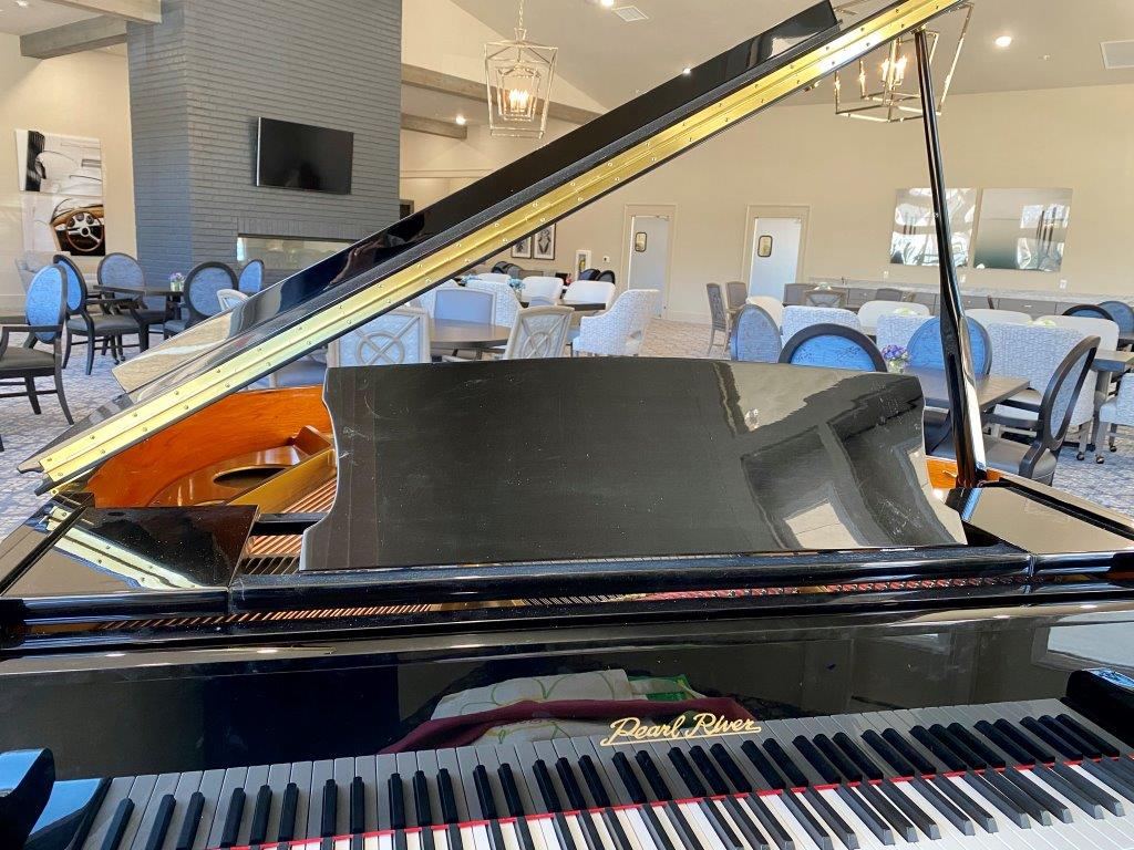 A grand piano is sitting in a room with a lot of chairs and tables.