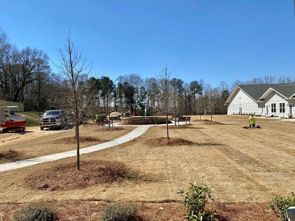 A large grassy field with a house in the background.