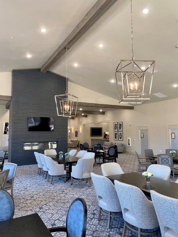 A large dining room with tables and chairs and a fireplace.