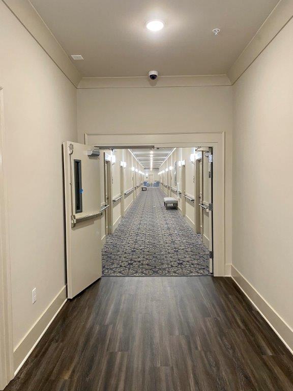 A long hallway with a door open and a carpeted floor.