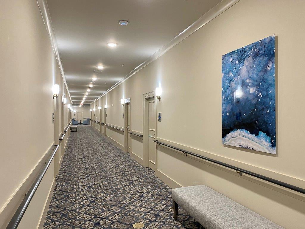 A long hallway with a bench and a painting on the wall.