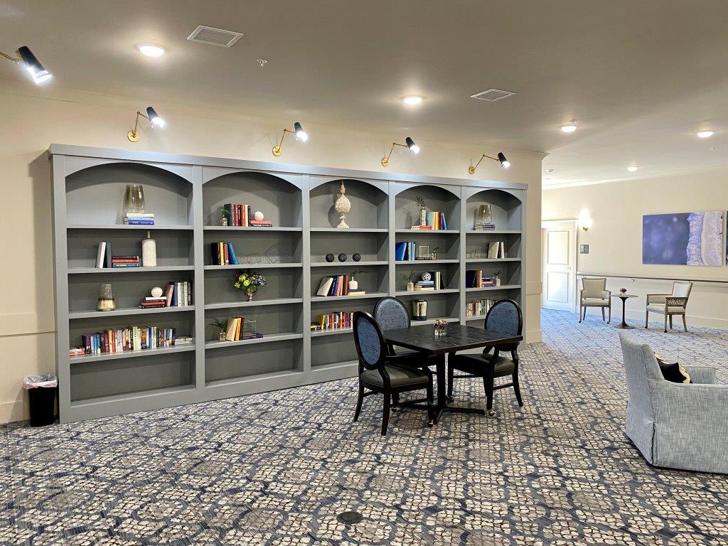 A living room with a table and chairs in front of a wall of bookshelves.