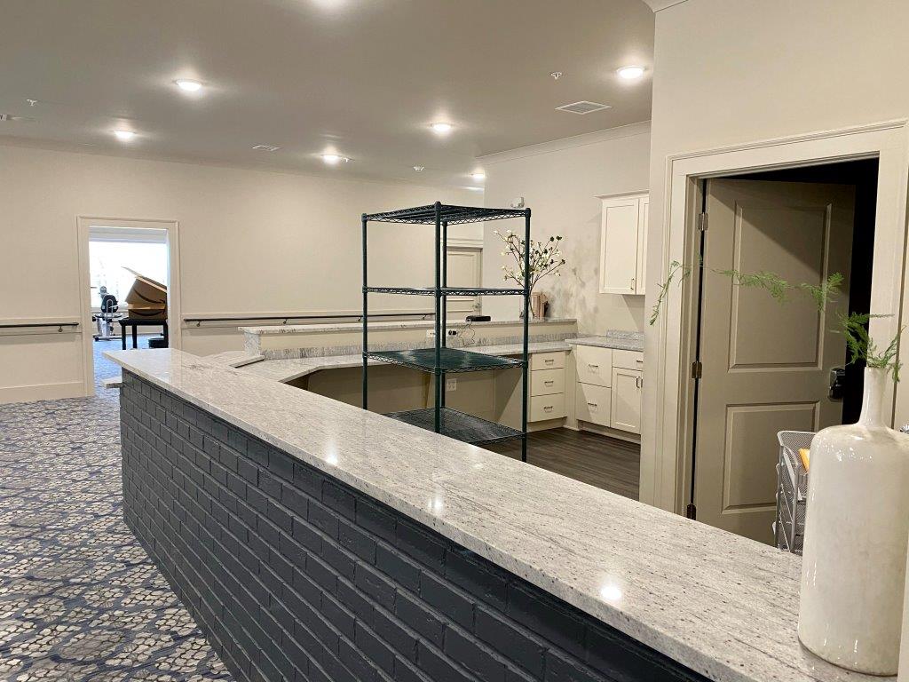 A kitchen with a large counter and a piano in the background.