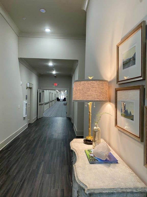 A long hallway with a table and a lamp in the middle.