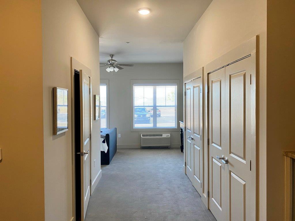 A long hallway with a lot of doors and a window.