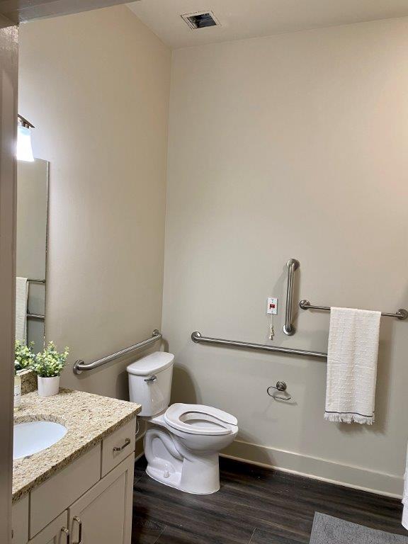 A bathroom with a toilet , sink and mirror.