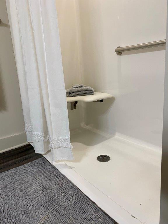 A bathroom with a walk in shower with a seat.