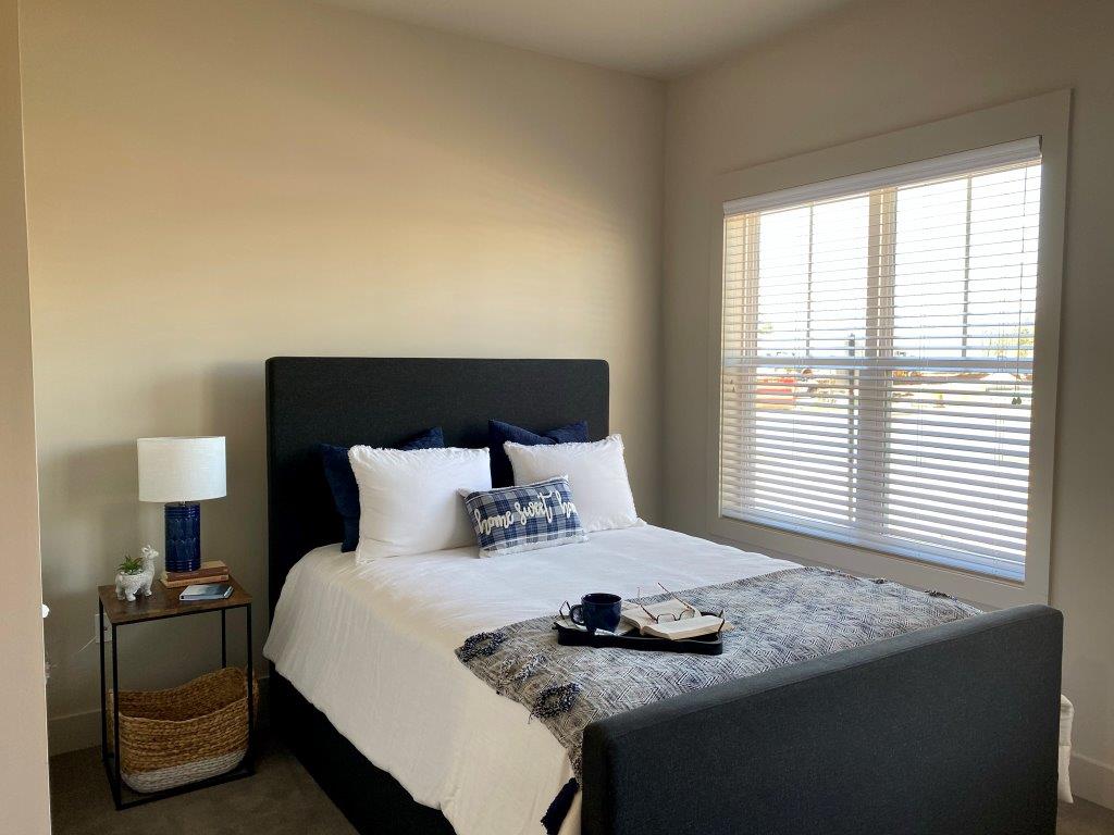 A bedroom with a bed , nightstand , lamp and window.
