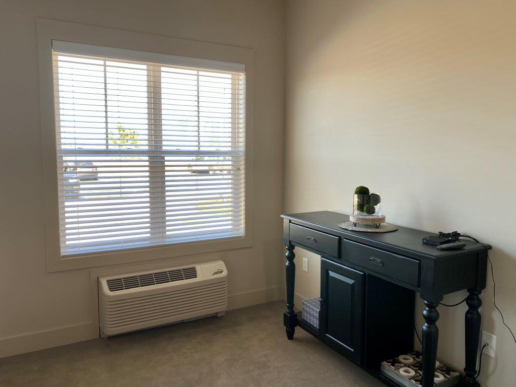 A room with a table and a window with blinds.