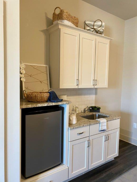A kitchen with white cabinets , granite counter tops , a sink and a refrigerator.