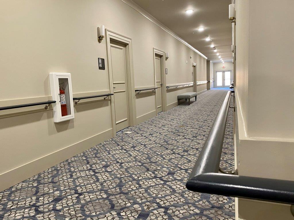 A long hallway with a fire extinguisher on the wall.