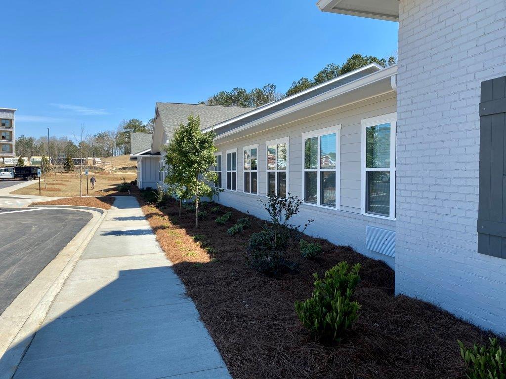 A white brick building with a sidewalk in front of it.