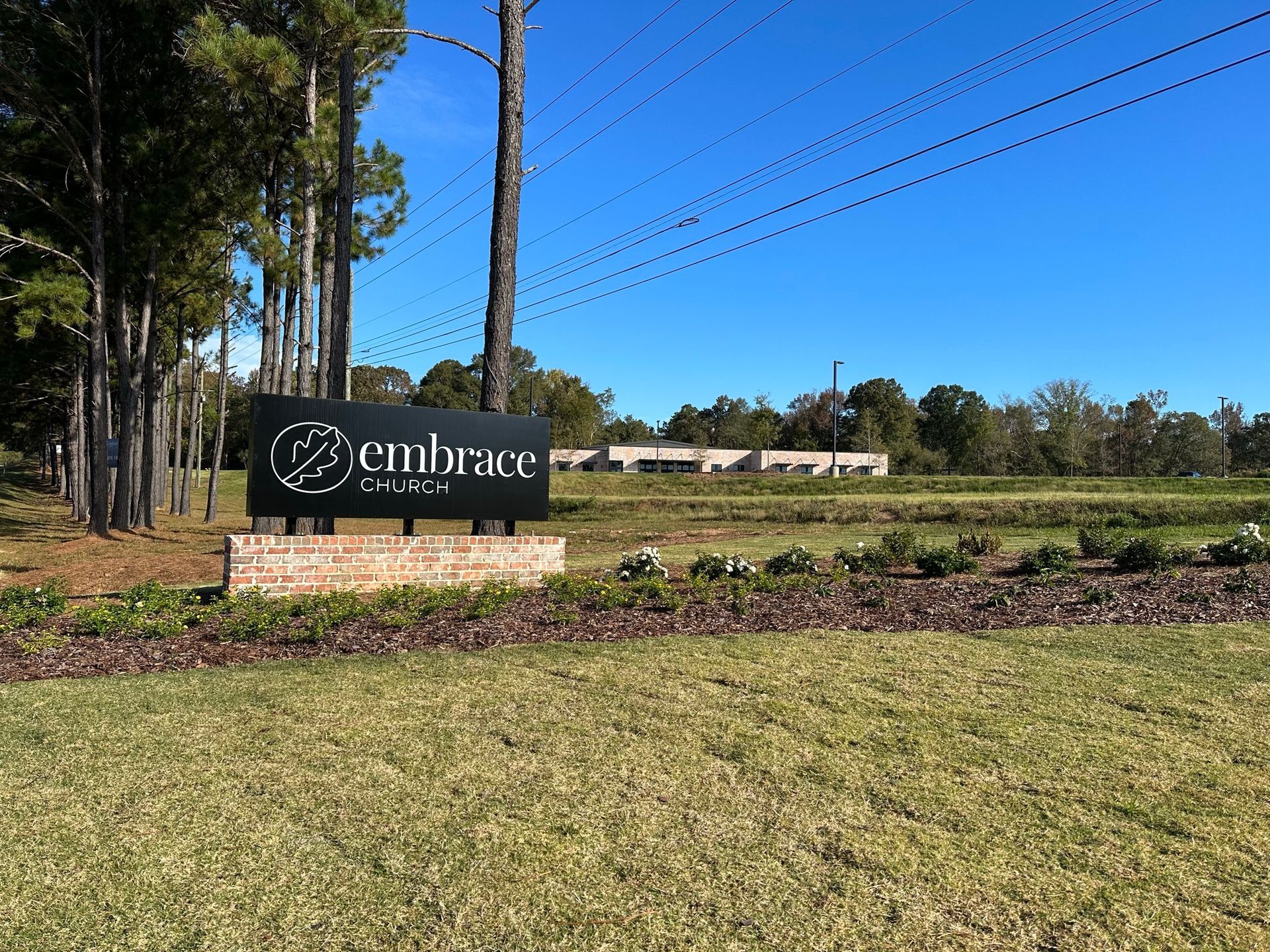 A sign that says embrace is in the middle of a grassy field.